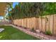 The backyard is surrounded by tall green trees, artificial turf, a block wall, and a wooden fence at 2501 Muirfield Ave, Henderson, NV 89074