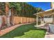 This property has a well maintained backyard with artificial turf, desert landscaping, a wooden fence, and covered patio at 2501 Muirfield Ave, Henderson, NV 89074