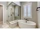 Bright bathroom showcasing a modern tub, a glass-enclosed shower, and a window with plantation shutters for natural light at 253 Malpaso St, Las Vegas, NV 89138