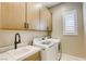 Functional laundry room equipped with modern washer and dryer, storage cabinets, and a sink for added convenience at 253 Malpaso St, Las Vegas, NV 89138