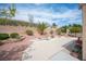 Serene backyard with desert landscaping, mature palm trees, and an extended patio area perfect for entertaining at 2737 Tumble Brook Dr, Las Vegas, NV 89134