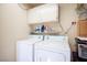 Bright laundry room featuring a washer, dryer, overhead cabinets and practical shelving for storage solutions at 2737 Tumble Brook Dr, Las Vegas, NV 89134
