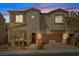 Charming two-story home featuring a welcoming entrance, two-car garage, and landscaped front yard at dusk at 3038 Villanelle Ave, Henderson, NV 89044