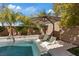 Backyard pool features in-pool lounge chairs, lush landscaping, and shade with an umbrella at 3038 Villanelle Ave, Henderson, NV 89044