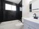 Modern bathroom featuring black marble tiled walls, bathtub, and a gray vanity at 3115 Wright Ave, North Las Vegas, NV 89030