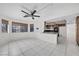 Bright, open-plan room with white tiled floors, ceiling fan, and adjacent kitchen area at 3382 Montessouri, Las Vegas, NV 89117