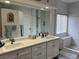 Bright bathroom featuring double sinks, quartz countertops, white cabinets, and a luxurious shower at 3749 Climbing Rose St, Las Vegas, NV 89147
