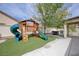 Lush backyard with play structure, artificial grass, and dining area with stone pavers at 3760 Candytuft Ridge Ave, North Las Vegas, NV 89081