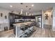 The modern kitchen features dark wood cabinets, stainless steel appliances and a granite island with bar stool seating at 415 Carsin Wayne Ct, North Las Vegas, NV 89031
