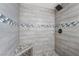 Close up of renovated tiled shower with rain shower head and pebble floor at 5069 Hallet Dr, Las Vegas, NV 89122