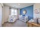 Charming Bedroom with white crib, cozy armchair, and blue accent wall, creating a serene and inviting space at 7915 Pandora Sky St # 403, North Las Vegas, NV 89084