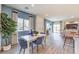 Open-concept living space with dining area featuring a white table, blue chairs, and bright natural light at 7915 Pandora Sky St # 403, North Las Vegas, NV 89084