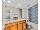 Bright bathroom featuring a bathtub with shower, wooden cabinets and a large mirror at 8811 Pauley Hills St, Las Vegas, NV 89131