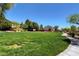Open common area with lush green grass, mature trees, and a concrete walking path at 8811 Pauley Hills St, Las Vegas, NV 89131
