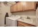 Functional laundry room with a washer, dryer, sink, and storage cabinets at 8811 Pauley Hills St, Las Vegas, NV 89131