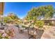 Serene backyard featuring a stone patio, lush landscaping, and comfortable seating areas at 10290 Profeta Ct, Las Vegas, NV 89135