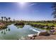 Picturesque pond reflecting the clear blue sky, surrounded by lush greenery and a golf course at 10290 Profeta Ct, Las Vegas, NV 89135