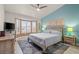 Bright bedroom featuring a large window, ceiling fan, and neutral toned walls with light-colored wooden furniture at 10921 Grand Haven Ave, Las Vegas, NV 89134