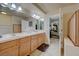 Bathroom with double sinks, wooden cabinets, and an open doorway to a bedroom at 1131 Sax Fifth Ave, Henderson, NV 89052
