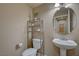 Cozy powder room featuring a pedestal sink, round mirror, and a shelving unit for storage at 1131 Sax Fifth Ave, Henderson, NV 89052