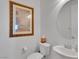 Bright white half-bath features a framed painting, round mirror, and modern fixtures at 12249 Catanzaro Ave, Las Vegas, NV 89138