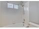 Bright bathroom featuring white tile, shower head and a tub with a window at 1660 Cloister Ave, Henderson, NV 89014