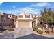 Two-story house featuring desert landscaping, a three-car garage, and shuttered windows under a vibrant blue sky at 235 Desert Arroyo Ct, Henderson, NV 89012