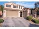 Two-story home with a three car garage, desert landscaping, and a tile roof under a blue sky at 235 Desert Arroyo Ct, Henderson, NV 89012