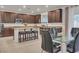 A view of the kitchen featuring a large island, dark cabinets, granite countertops, and a dining table with chairs at 235 Desert Arroyo Ct, Henderson, NV 89012
