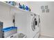 A bright laundry room with a front-load washer and dryer, storage shelves, and laundry supplies at 235 Desert Arroyo Ct, Henderson, NV 89012