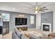 A gray living room with a fireplace, a ceiling fan, a sectional sofa, and a flatscreen television at 235 Desert Arroyo Ct, Henderson, NV 89012