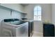 Efficient laundry room with modern front-load machines, overhead shelving, and a window for natural light at 4642 Chirping St, North Las Vegas, NV 89031