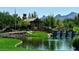 Scenic community entrance featuring a covered walkway, a stone bridge, a tranquil pond, and lush greenery at 5 Clear Crossing Trl, Henderson, NV 89052