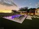 Beautiful backyard pool area at dusk with lounge chairs and an outdoor kitchen at 5 Clear Crossing Trl, Henderson, NV 89052