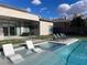 Inviting backyard pool with submerged lounge chairs, sun loungers, an outdoor dining set, and a manicured lawn at 5 Clear Crossing Trl, Henderson, NV 89052