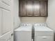 Bright laundry room featuring a washer and dryer, plus upper cabinets for storage at 5340 Kennedy Hill Ave, Las Vegas, NV 89139