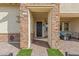 Close-up of a home's entrance, featuring a stone archway, black metal door and a cozy sitting area at 746 Purple Knoll Walk, Henderson, NV 89011
