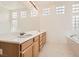 Bright bathroom featuring double sinks, a large mirror, glass block windows, and a soaking tub at 7568 Shadow Estates Way, Las Vegas, NV 89113