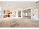 Open-concept living space featuring kitchen with stainless steel appliances and an airy carpeted living room at 7568 Shadow Estates Way, Las Vegas, NV 89113