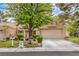 Tan home features a two-car garage, mature tree, and a well-manicured front yard at 8513 Glenmount Dr, Las Vegas, NV 89134