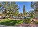 Community pool showcasing lush landscaping, mature trees, lounge chairs, and vibrant grass at 8861 Hampton Green Ave, Las Vegas, NV 89129