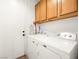Bright laundry room features a Maytag washer and dryer and upper wood cabinets for storage at 9037 Picket Fence Ave, Las Vegas, NV 89143
