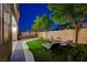 Picturesque backyard featuring an artificial lawn, shade trees, dining and lounge seating at 9413 Artesian Oak Ct, Las Vegas, NV 89149