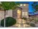 Attractive home with decorative stone accents, illuminated walkway, lush landscaping, and a warm, inviting entrance at 9413 Artesian Oak Ct, Las Vegas, NV 89149