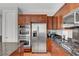 A stainless steel fridge is surrounded by wood cabinets and granite counters in this kitchen at 9413 Artesian Oak Ct, Las Vegas, NV 89149