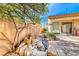 A shot of the backyard with decorative rockwork and well maintained plants, a wooden door and sliding glass doors at 14 Hunt Valley Trl, Henderson, NV 89052
