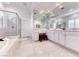 Bright bathroom featuring double sinks, large mirrors, a walk-in shower, and a soaking tub at 14 Hunt Valley Trl, Henderson, NV 89052