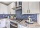 Modern kitchen featuring white cabinets, stainless steel appliances, granite countertops, and a stylish tile backsplash at 1921 Lewis Bay Ave # Lot 21, North Las Vegas, NV 89084