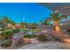 Lush backyard with a putting green, desert landscaping, and a covered patio area at 2248 Carrizo Way, Henderson, NV 89052