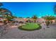 Putting green nestled among palm trees and desert landscaping with custom night lighting at 2248 Carrizo Way, Henderson, NV 89052